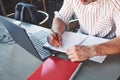 Writing on the white paper. Particle view of freelance man working on the project with laptop and notepads on table