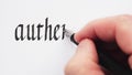 Writing of word authenticity. Hands writing with a pen. Calligraphy closeup.