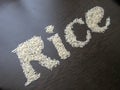 Writing the word Rice with rice seeds on a table with brown wooden background