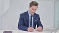 Writing Young Businessman doing Paperwork in Office Royalty Free Stock Photo