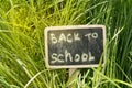 Written back to school, chalked on a blackboard against a green grass background, bright sunlight Royalty Free Stock Photo