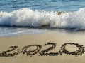 2020 written by hand on the sand beach with beautiful wave and clear blue sea. Handwritten lettering numbers 2020 on sea shore Royalty Free Stock Photo