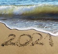 2021 written by hand on the sand beach with beautiful wave and clear blue sea. Handwritten lettering numbers 2021 on sea shore Royalty Free Stock Photo