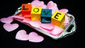 Written LOVE on colored wooden cubes with pink cloth hearts on a silver plastic tray Royalty Free Stock Photo