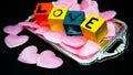 Written LOVE on colored wooden cubes with pink cloth hearts on a silver plastic tray Royalty Free Stock Photo