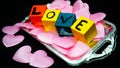 Written LOVE on colored wooden cubes with pink cloth hearts on a silver plastic tray Royalty Free Stock Photo
