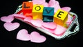 Written LOVE on colored wooden cubes with pink cloth hearts on a silver plastic tray Royalty Free Stock Photo