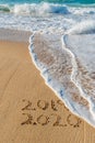 2019 2020 written in the sand with a wave erasing 2019