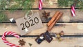 2020 writting on little paper putwooden background with spices, candy canes and chocolat