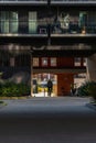 Dark facade of modern block of flats with glass balconies and small tunnel with riding cyclists