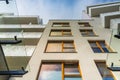 Modern facade of block of flat in new estate with wooden window frames and decorations on balcony