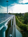 Long concrete footbridge over long street with metal railings at sunny cloudy day