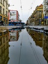 Cityscape of Pilsudskiego street with riding tram reflected in puddle