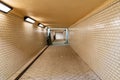 Long tunnel with white tiles under train platforms