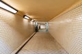 Long tunnel with white tiles under train platforms