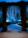 Monument to Fryderyk Chopin behind concrete arch of entrance to park at night