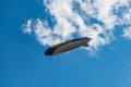 Big airship with Goodyear logo flying over market square at sunny cloudy day