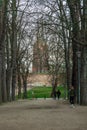 Beautiful long and wide walking path with high old trees on both sides with two towers of