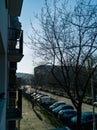 Beautiful morning view from apartment balcony to city street with parked cars and riding cyclist