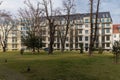 Small green square with small trees and bushes next to new estate with modern apartment buildings