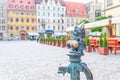 Wroclaw, Poland, May 7, 2019: Dwarf is sitting on street water tap on Rynek Market Square Royalty Free Stock Photo