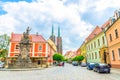 Wroclaw, Poland, May 7, 2019: Monument on square and cobblestone road street with green trees Royalty Free Stock Photo