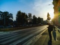 Man standing next to pedestrian crossing with long shadow waiting for green light at beautiful