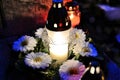 Candle and flowers on grave in the night