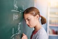 This is wrong. a stressed young elementary school kid writing answers to math questions on a green chalkboard in the