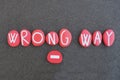 Wrong Way, creative sign composed with red colored stone letters over black volcanic sand