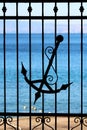 Wrought iron fence with decorative elements and silhouette of old antique vintage handmade anchor with decorations Royalty Free Stock Photo