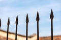 Wrought iron fence with sharp points on blue sky with clouds Royalty Free Stock Photo