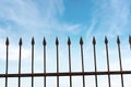 Wrought iron fence with sharp points on blue sky with clouds Royalty Free Stock Photo