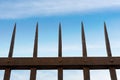 Wrought iron fence with sharp points on blue sky with clouds Royalty Free Stock Photo