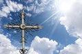 Wrought Iron Religious Cross on Beautiful Blue Sky with Clouds and Sun Rays Royalty Free Stock Photo