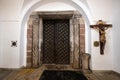 Wrought iron wooden doors to an old 12th-century church and a wooden crucifix, Poland Royalty Free Stock Photo