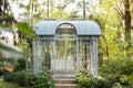 Wrought metal gazebo in summer garden. Flowers in pots near porch. Sofa in spring gazebo. Large iron blue gazebo for relax outdoor Royalty Free Stock Photo