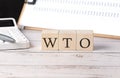 WTO - World Trade Organization word on a wooden block with clipboard and calculator