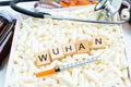 Wuhan keyword on wood block on medical pill with syringe