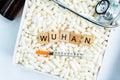 Wuhan keyword on wood block on medical pill with syringe