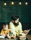 Wunderkind and genius concept. Father, teacher reading book, teaching kid, son, chalkboard on background. Boy child in