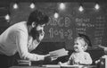 Wunderkind and genius concept. Father, teacher reading book, teaching kid, son, chalkboard on background. Dad wants to