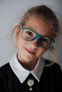 Wunderkind little caucasian girl in blue eyeglasses and school black and white uniform smiling portrait