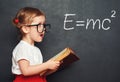 Wunderkind little girl schoolgirl with a book from the blackboar Royalty Free Stock Photo