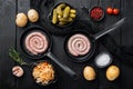 Wurst or Bratwurst with Fermented Cabbage  Pickled Cucumbers  and Spices in cast iron frying pan  on black wooden table background Royalty Free Stock Photo