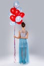 Wwoman wearing beautiful dress with a lot of colorful balloons