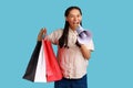 Wxcited woman screaming in megaphone and holding shopping bags, advertising discounts. Royalty Free Stock Photo