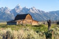 Tourist man takes photos of John Moulton Barn at Mormon Row in Grand Teton National Park on a clear