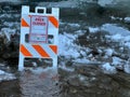 "area closed" board on a flowing water, melting snow around