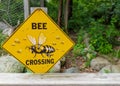 "Bee Crossing" sign mounted on fence post with blurred background